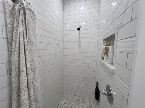 a white tiled shower with a shower curtain in a bathroom at ADA Friendly and AC Little House on the Ferry in Albany
