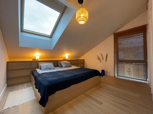 a bedroom with a bed and a large window at Pine Attic - new & cozy 3 bedroom apartment,Nida in Nida