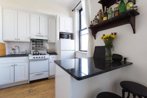 a kitchen with white cabinets and a black counter top at Sunny Stylish West Village Condo in New York