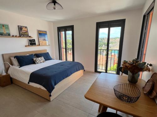 um quarto com uma cama, uma mesa e janelas em Canta la Mar - Vue exceptionnelle em Collioure