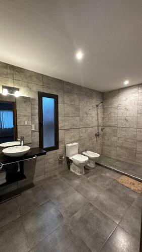 a bathroom with two sinks and a toilet and a sink at Chacras House in Chacras de Coria