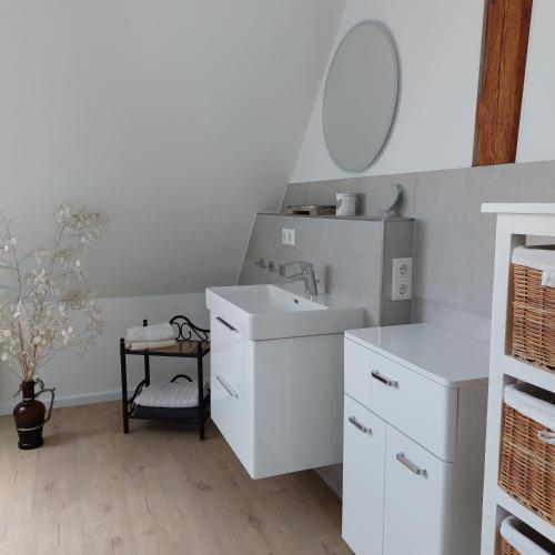a white bathroom with a sink and a mirror at FeWo Dreiseitenblick Komfort mit 2 Schlafzimmern in Bad Doberan