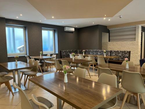 um restaurante com mesas e cadeiras de madeira e janelas em Skyline Hotel Hannover em Hanôver