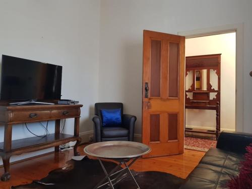a living room with a couch and a tv and a table at The Heritage - located in in the center of Glenelg in Glenelg