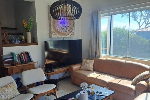 un salon avec un canapé et une télévision à écran plat dans l'établissement casa perfeita de sonho e completa, à Armacao dos Buzios