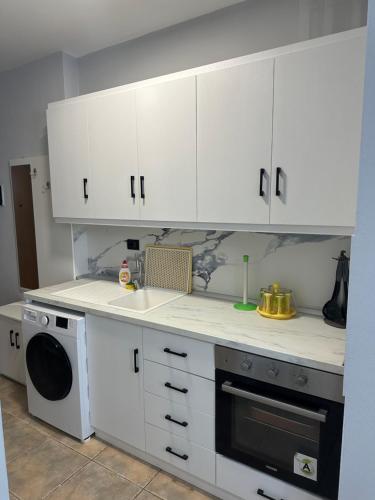 La cuisine est équipée de placards blancs, d'un évier et d'un lave-vaisselle. dans l'établissement Apartment 50m Away From The Beach, à Durrës