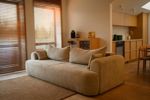 a living room with a couch and a kitchen at Pine Attic - new & cozy 3 bedroom apartment,Nida in Nida