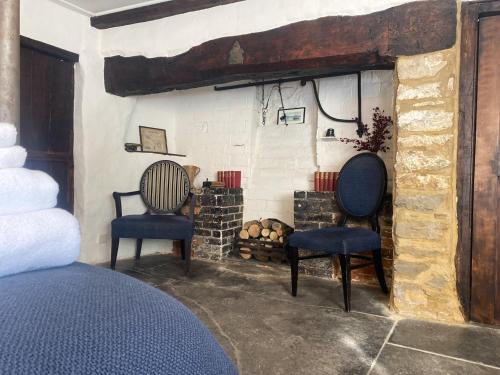 dwa krzesła siedzące w pokoju z kominkiem w obiekcie The New Inn w mieście Yeovil
