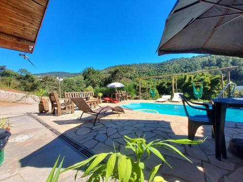 a patio with a table and chairs and a pool at Pousada Pé na Montanha in Socorro