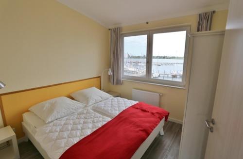 1 dormitorio con 1 cama con manta roja y ventana en Am Rundsteg 12, en Burgtiefe auf Fehmarn 