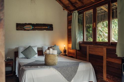 a bedroom with a bed with white sheets and windows at Villa Iamani in Arraial d'Ajuda