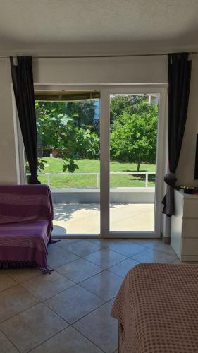 a bedroom with a sliding glass door to a yard at Apartmani Natasa in Vantačići