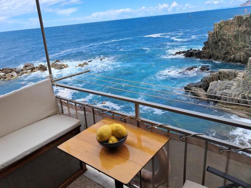 a bowl of fruit on a table on a balcony with the ocean at Il mare in casa in Riomaggiore