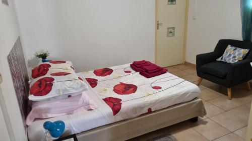 łóżko w pokoju z krzesłem i łóżkiem z czerwonymi różami w obiekcie Hibiscus et Miro w mieście Ducos