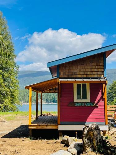 a small red house with a deck on the side at Gracies Grotto Cabin in Powell River