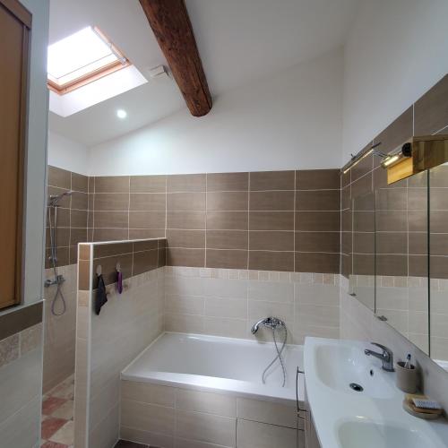 une salle de bain avec une baignoire et un lavabo dans l'établissement Entre Mer & Montagne - Location du Samedi au Samedi uniquement - rental only from Saturday to Saturday, à Laurens
