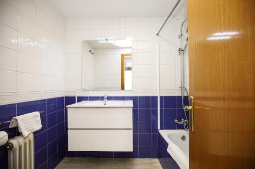 baño azul y blanco con lavabo y bañera en Apartamento con dos grandes terrazas en Girona, en Girona
