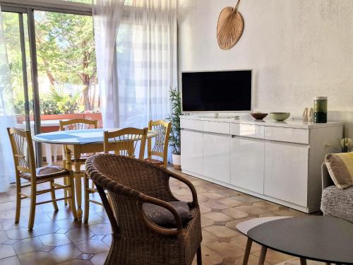 un salon avec une télévision, une table et des chaises dans l'établissement Banyuls-sur-Mer, T3, Rez-de-chaussée avec terrasse, parking, proche Thalassothérapie - FR-1-309-295, à Banyuls-sur-Mer
