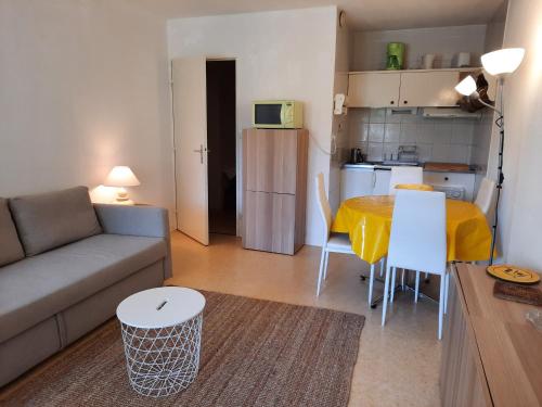 un salon avec un canapé et une table et une cuisine dans l'établissement Appartement Lumineux à Seignosse, Proche Plage, Commerces et Activités, Parking, Wifi et Balcon - FR-1-239-813, à Seignosse