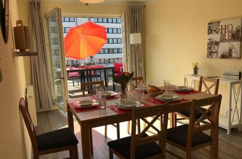 - une salle à manger avec une table et un parasol rouge dans l'établissement Am Rundsteg 8, à Burgtiefe auf Fehmarn 