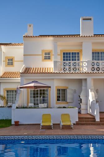 a house with two chairs next to a swimming pool at BALAIA PLAZA AL - Ideal para Familias in Albufeira