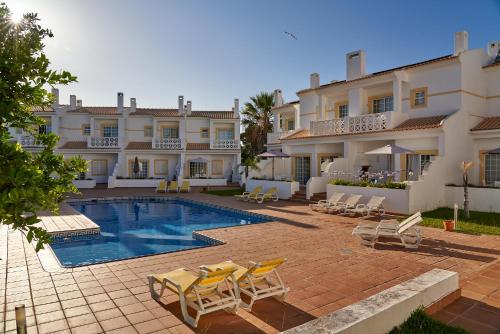 a hotel with a swimming pool and chairs and a building at BALAIA PLAZA AL - Ideal para Familias in Albufeira