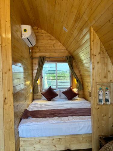 1 cama en una cabaña de madera con ventana en Buru Resort, en Ghātsīla