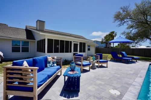 d'une terrasse avec un canapé bleu et des chaises à côté de la piscine. dans l'établissement Southern Mermaid Cottage- Pet Friendly Fenced, à Saint Joe Beach