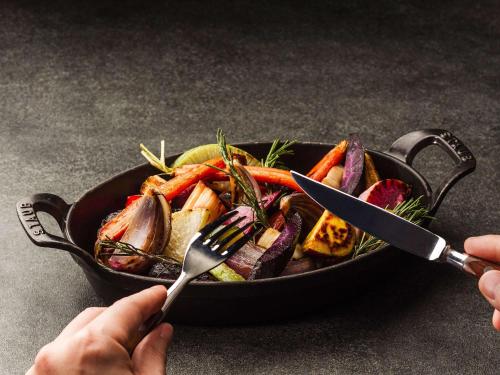 a person holding a plate of vegetables with a fork and knife at Mercure Wakayama Kushimoto Resort & Spa in Kushimoto