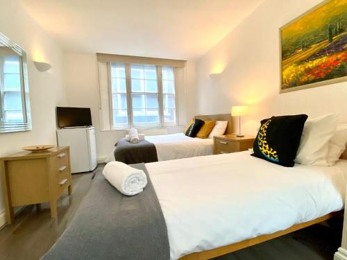a room with two beds and a tv and two windows at Shoreditch & Liverpool Street Room B in London