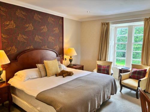 a bedroom with a bed with a stuffed animal on it at Blackaddie House Hotel in Sanquhar