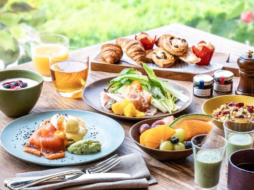 Grand Mercure Lake Biwa Resort & Spa في ناغاهاما: طاولة خشبية مليئة بالأطباق الغذائية والمشروبات