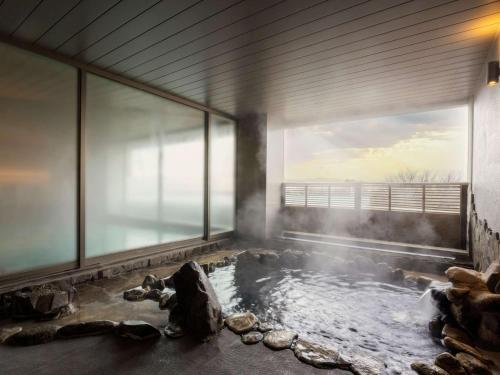 長野的住宿－Mercure Nagano Matsushiro Resort & Spa，带大窗户的客房内的热水浴池