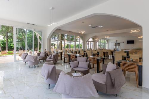 ein Esszimmer mit Stühlen, Tischen und Fenstern in der Unterkunft Hotel Emaus in Novigrad Istria