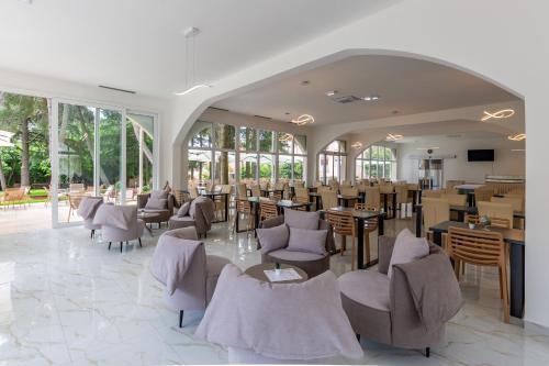 una sala da pranzo con sedie, tavoli e finestre di Hotel Emaus a Novigrad Istria