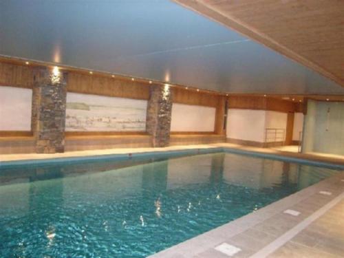 a large swimming pool with blue water in a building at Cohennoz Le Cernix - Appartement montagne avec piscine proche pistes in Cohennoz