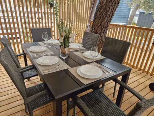 een zwarte tafel met stoelen, borden en wijnglazen bij Paradiso mobile home in Biograd na Moru