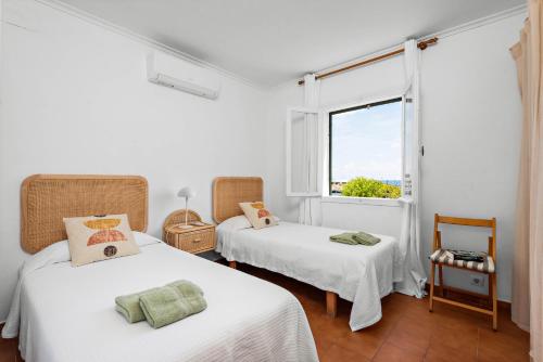 two beds in a white room with a window at Mon Palau in Sant Lluis
