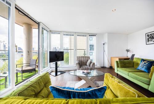 a living room with a green couch and a tv at Austin David Apartments ExCeL in London