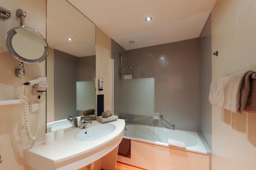 a bathroom with a sink and a tub and a mirror at Familienhotel Trebesingerhof in Trebesing