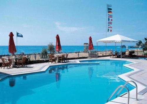 ein Pool mit Tischen und Sonnenschirmen und das Meer in der Unterkunft Corfu Glyfada Menigos Resort 24 in Pelekas