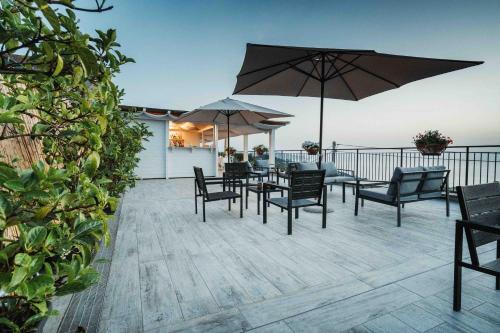 eine Terrasse mit Stühlen, Tischen und Sonnenschirmen in der Unterkunft Complesso San Francesco in Massa Lubrense