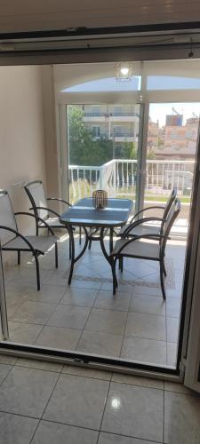 a table and chairs in a room with a view of a balcony at Stella apartments in Olympiaki Akti