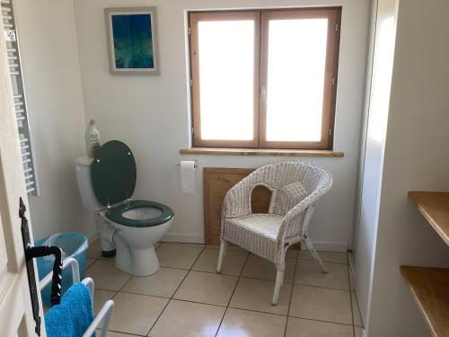 a bathroom with a toilet and a chair and a window at La Biste in Mirepoix