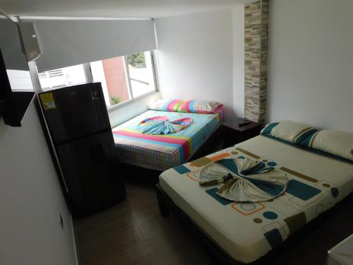 a small room with two beds and a window at El Velero Apartamentos By DANP in Santa Marta