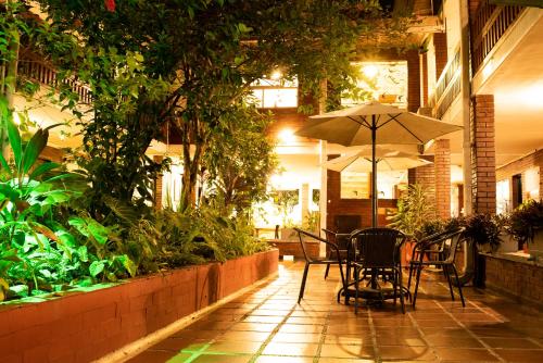 Hotel Camoruco في يوبال: طاولة وكراسي مع مظلة في ساحة الفناء
