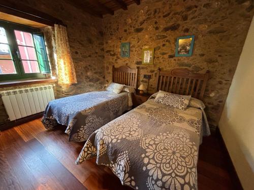 1 dormitorio con 2 camas y pared de piedra en Eira de Bergondo, en Bergondo