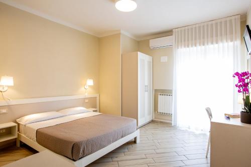 a bedroom with a bed and a large window at Hotel Lungomare in Cervia
