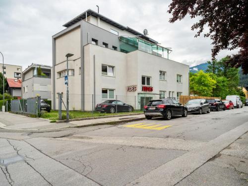 ein weißes Gebäude mit Autos auf einem Parkplatz in der Unterkunft Gorgeous Apartment in Innsbruck near Ambras Castle in Innsbruck