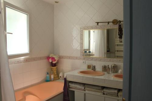 une salle de bain avec un lavabo, une baignoire et un miroir dans l'établissement maison dans un charmant village au cœur des garrigues, à Sainte-Croix-de-Quintillargues